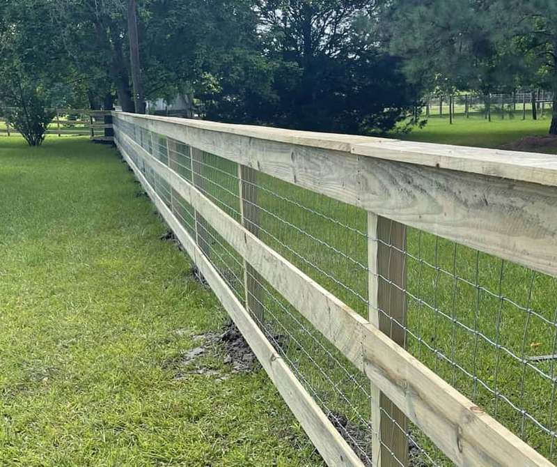 Ranch-style wood and wire fence running along a green lawn in the Boise area